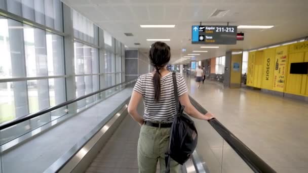 공항 에스컬레이터에 보호용 마스크를 쓴 젊은 여성 의 4K 영상 — 비디오
