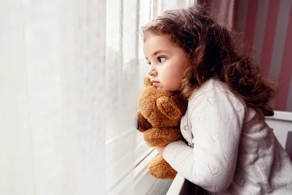 Маленькая милая девочка смотрит от окна до дождя с грустью становится скучно . — стоковое фото