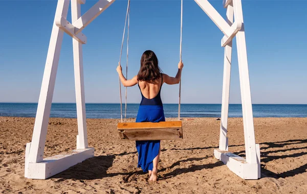 Krásná žena houpající se na houpačce na jemném písku těší idylickou scénu slunce, písku a moře. Krásná písečná pláž v Antalyi. — Stock fotografie