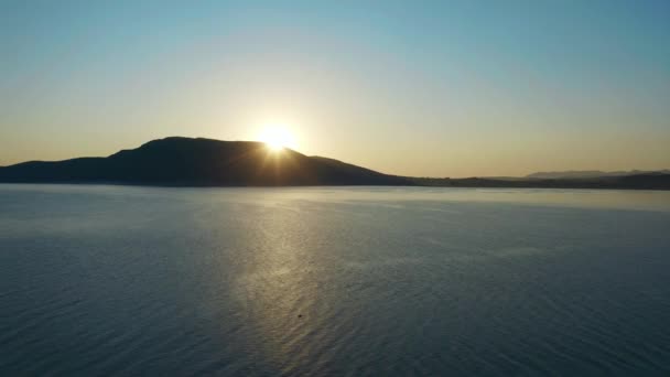 日の出とシルエットの丘の背景を持つ湖のFHDビデオ空中ビュー。旅行観光のコンセプト. — ストック動画