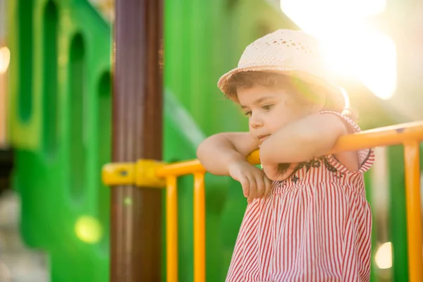 Маленькая симпатичная девочка, играющая летом на детской площадке под открытым небом — стоковое фото