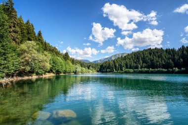 Kabarık bulutlu gökyüzü ve dağ zeminli güzel bir göl manzarası. Seyahat Turizmi.