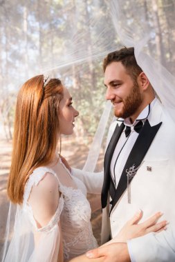 Gelin ve damat düğün duvağı altında gülümsüyor. Yüksek kalite fotoğraf