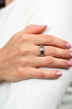 Beyaz kumaş arka planda duran gümüş yüzüklü kadın elinin yakın çekimi. Yüksek kalite fotoğraf