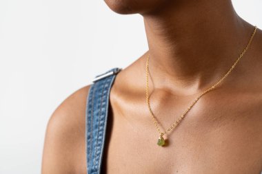 Yeşil değerli kolyesi olan altın kolye takan bir kadın. Yüksek kalite fotoğraf