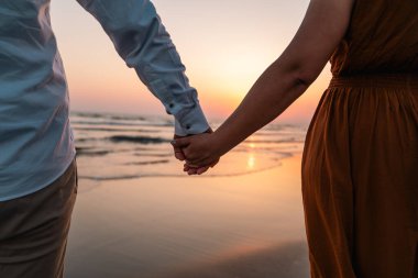 Gün batımında kumsalda el ele tutuşan çift. Yüksek kalite fotoğraf