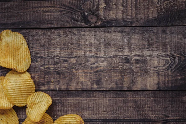 Knusprige Kartoffelchips auf Holzuntergrund. Chips gestartet — Stockfoto
