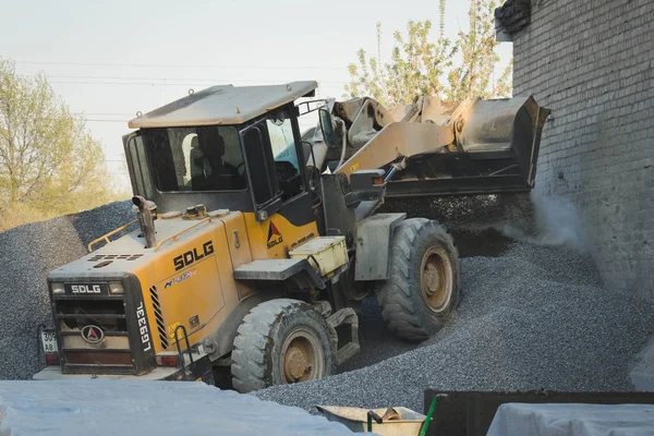 Voronezh region, russland, 25. april 2019. traktorladungen schotter bei der produktion von beton. Ein gelber Traktorlader fährt in Schutthaufen. Schaufel lädt den Beton. — Stockfoto