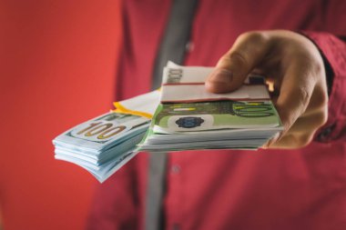 kırmızı gömlekli bir adam elinde kırmızı bir arka plan üzerinde faturaları bir tomar tutar