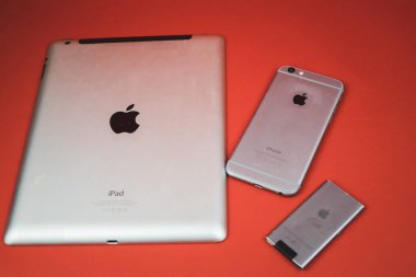 Moskova, Rusya - 25 Nisan 2019: ipod, iphone ve ipad arka arkaya yatıyor . Kırmızı arka planda üretim. elma ürünleri. Yapımcı: Apple Inc..