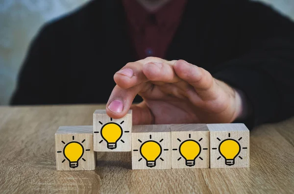Hand geplukt een houten kubussen met de gele gloeilamp symbool op houten tafel. Nieuwe concepten voor idee, innovatie en oplossing. — Stockfoto