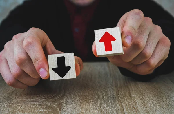 two wooden cubes in the hands of a man of red and black, red means growth and development, and black arrow means fall and degradation, extinction, regression