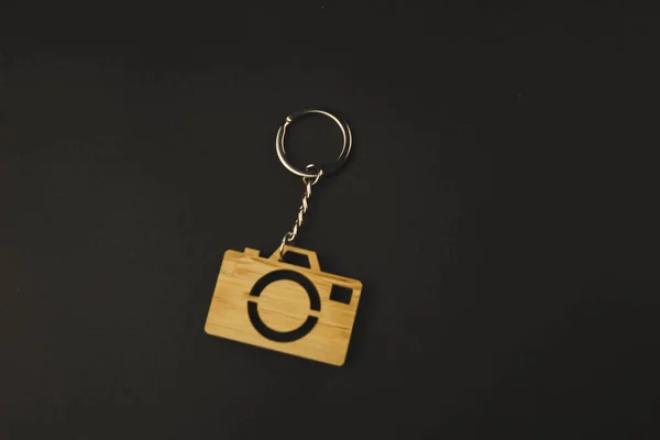 Gingillo in legno a forma di macchina fotografica su sfondo nero. portachiavi — Foto Stock