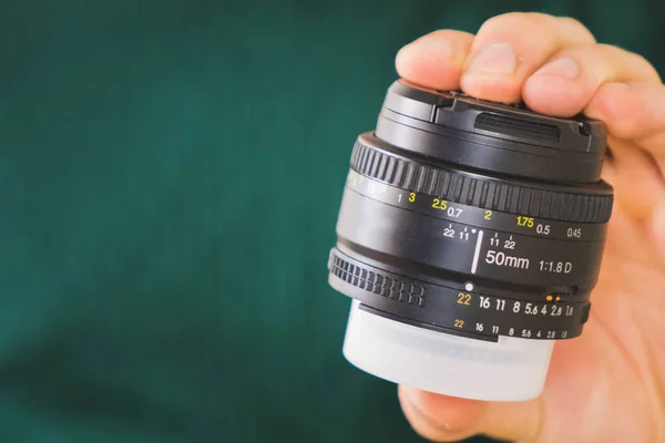 Moskou, Rusland-mei 03 2019: Lens Nikkor 50 mm 1.8 g voor Nikon SLR camera. Fast lens Nikkor. lens in man's hand op groene achtergrond. — Stockfoto