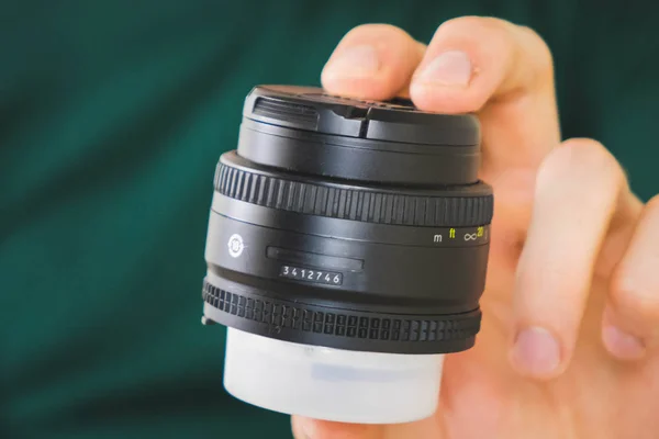 Moskou, Rusland-mei 03 2019: Lens Nikkor 50 mm 1.8 g voor Nikon SLR camera. Fast lens Nikkor. lens in man's hand op groene achtergrond. — Stockfoto