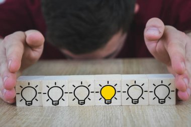 bir el, diğer tüm lambalar söndürüldüğünde yanan lambalı bir küp tutar, bu da Yeni Fikir'i, yenilik ve çözüm kavramlarını sembolize eder..