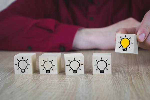 Hand geplukt een houten kubussen met de gele gloeilamp symbool op houten tafel. Nieuwe concepten voor idee, innovatie en oplossing. — Stockfoto