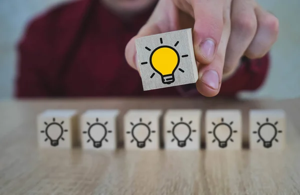 Hand geplukt een houten kubussen met de gele gloeilamp symbool op houten tafel. Nieuwe concepten voor idee, innovatie en oplossing. — Stockfoto