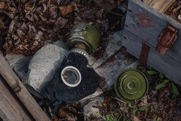 Garbage and human waste in nature. Torn gas mask in the grass in the fallen leaves in the autumn forest.