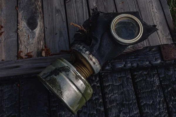 Garbage and human waste in nature. Torn gas mask in the grass in the fallen leaves in the autumn forest.