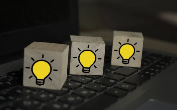 笔记本电脑键盘上有灯泡的木制立方体。 新概念、创新和解决方案概念 — 图库照片
