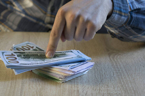Мужчина считает деньги в руке. Финансы, сбережения, зарплата и пожертвования
.