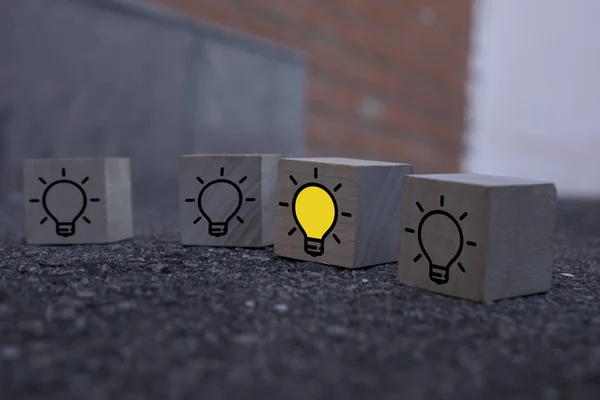 Creative idea, New idea, innovation and solution concept. wooden cubes with the yellow light bulb symbol on table, blue background, copy space