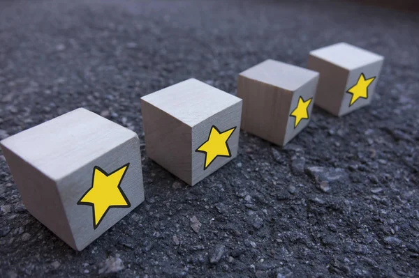 4 cubi di legno con un motivo di una stella gialla in piedi uno sopra l'altro su asfalto — Foto Stock