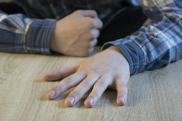 Mão de um homem adulto deitado em uma mesa de madeira — Fotografia de Stock