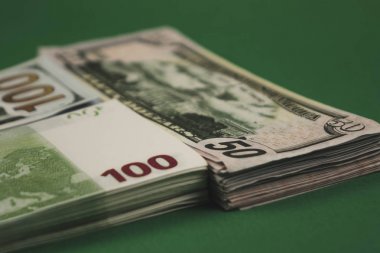 Dolar paketi, ruble ve yeşil arka plan üzerinde euro. Farklı büyüklükteki nakit yığınları. Ağır iş gücüyle kazan. Eski masada para tasarrufu.