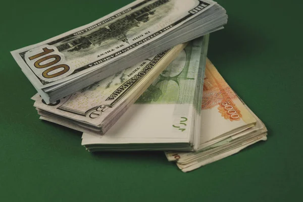 several wads of cash lying on top of each other on a green background