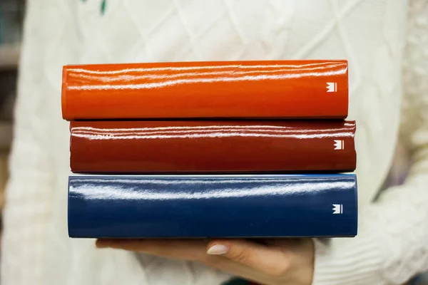 Drie grote boeken van rood, oranje en blauw in de handen van een meisje — Stockfoto