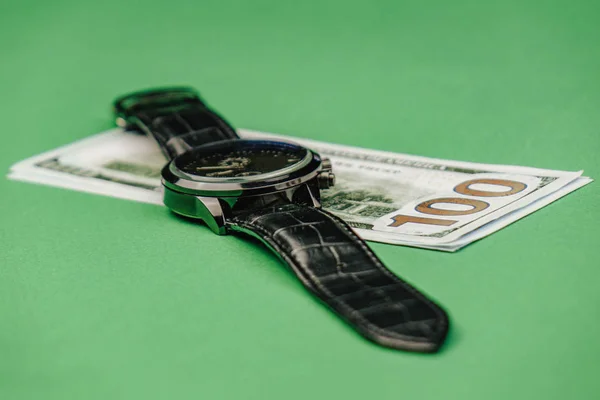 Wrist watches lying on a hundred dollar bill against a green background — Stock Photo, Image