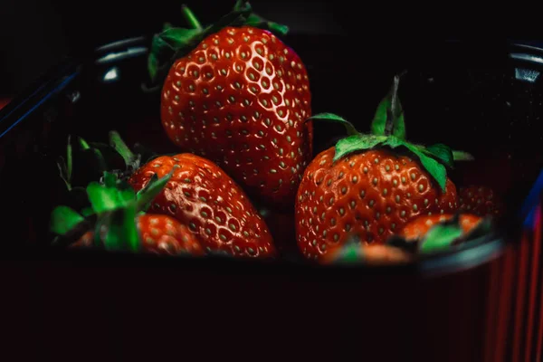 Fresas frescas y jugosas con hojas. Fresa sobre fondo rojo — Foto de Stock