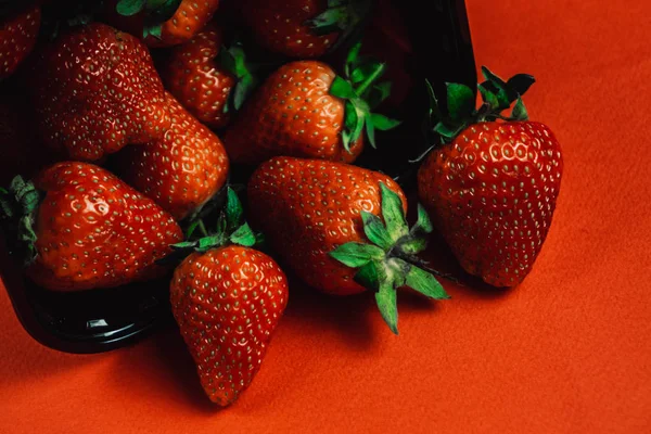 Frische saftige Erdbeeren mit Blättern. Erdbeere auf rotem Hintergrund — Stockfoto