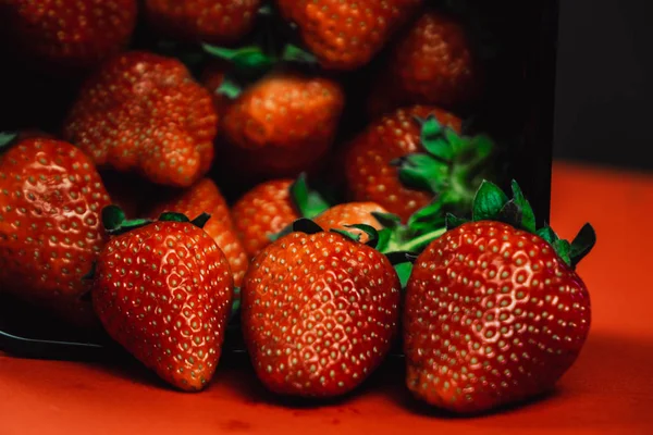 Fresas frescas y jugosas con hojas. Fresa sobre fondo rojo — Foto de Stock