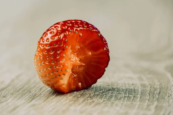 Gebissene Erdbeere auf weißem Holzhintergrund aus nächster Nähe — Stockfoto