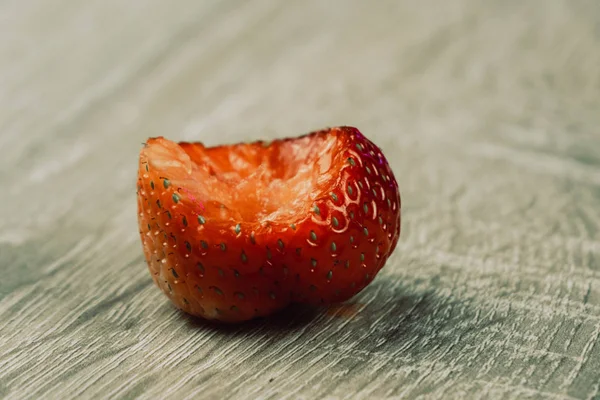 Gebissene Erdbeere auf weißem Holzhintergrund aus nächster Nähe — Stockfoto