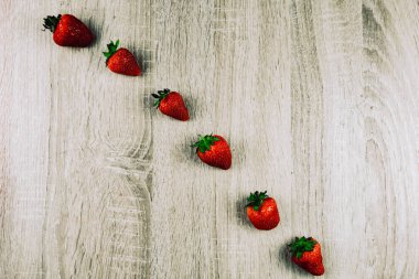 Olgun çilek tahta yüzeyi satırı. Mevsimlik bir kahvaltı olarak satırlardaki organik tatlı çilek. Bir çiftlik taze.