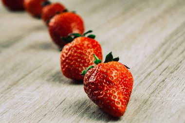 Olgun çilek tahta yüzeyi satırı. Mevsimlik bir kahvaltı olarak satırlardaki organik tatlı çilek. Bir çiftlik taze.