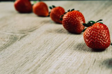 Olgun çilek tahta yüzeyi satırı. Mevsimlik bir kahvaltı olarak satırlardaki organik tatlı çilek. Bir çiftlik taze.