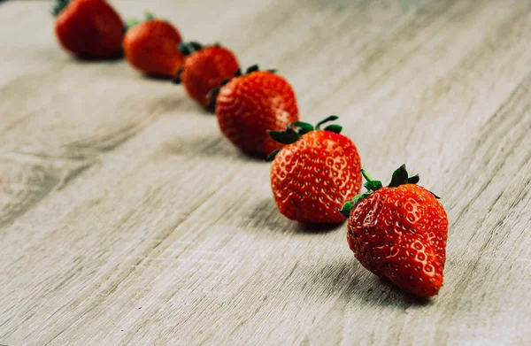 Filas de fresas maduras en la superficie de madera. Fresas dulces orgánicas en filas como desayuno de temporada. Fresco de una granja . — Foto de Stock