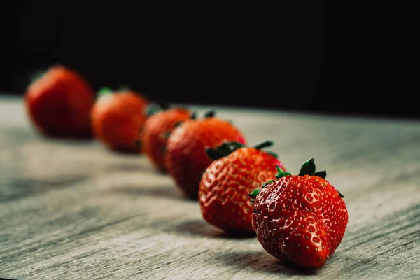 Filas de fresas maduras en la superficie de madera. Fresas dulces orgánicas en filas como desayuno de temporada. Fresco de una granja . — Foto de Stock