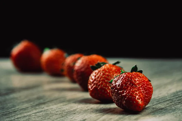 Filas de fresas maduras en la superficie de madera. Fresas dulces orgánicas en filas como desayuno de temporada. Fresco de una granja . — Foto de Stock