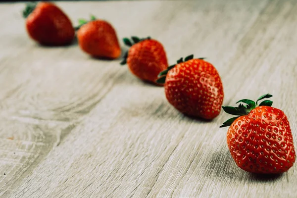 Filas de fresas maduras en la superficie de madera. Fresas dulces orgánicas en filas como desayuno de temporada. Fresco de una granja . — Foto de Stock