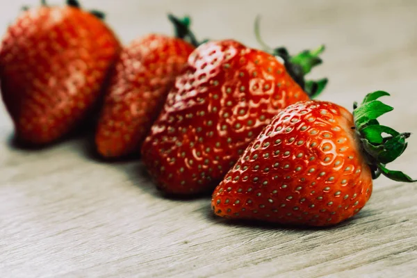 Filas de fresas maduras en la superficie de madera. Fresas dulces orgánicas en filas como desayuno de temporada. Fresco de una granja . — Foto de Stock