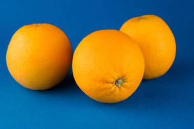 mavi bir arka plan üzerinde yatan üç bütün portakal