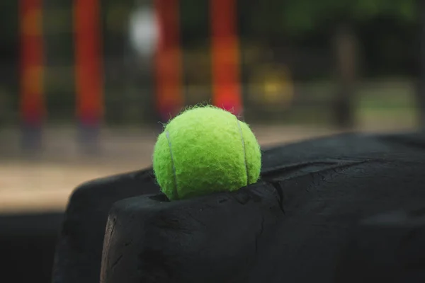 Pelota de tenis acostado en la rueda de goma en el campo de deportes — Foto de Stock