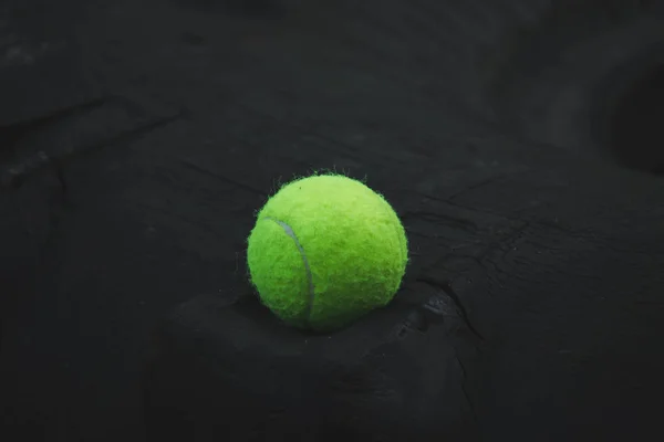 Pelota de tenis acostado en la rueda de goma en el campo de deportes — Foto de Stock