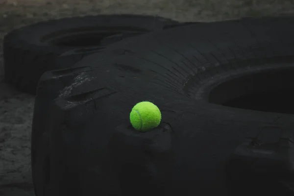 Μπάλα του τένις που βρίσκεται στο ελαστικό τροχό στο αθλητικό πεδίο — Φωτογραφία Αρχείου